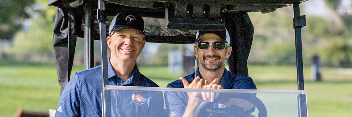 Two men smiling driving a golf cart