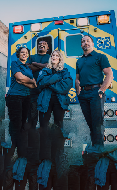 Four male and female paramedics standing by an ambulence